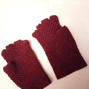 May include: A pair of burgundy fingerless gloves made of crocheted yarn.