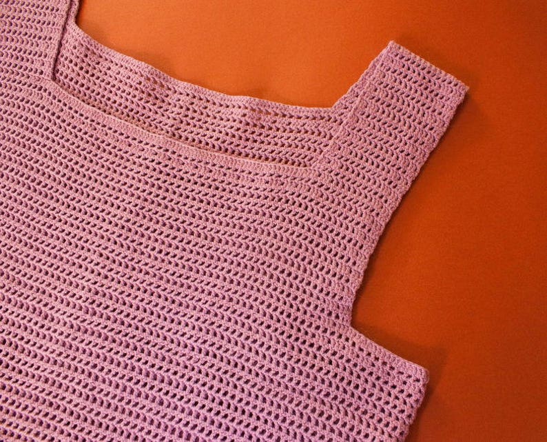 May include: A pink crocheted sleeveless top with a square neckline.