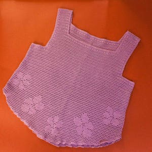 May include: A lavender crocheted tank top with a square neckline. The top has a delicate, open-stitch pattern.