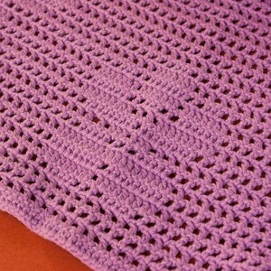 May include: A close-up of a purple crocheted blanket with a diamond pattern.