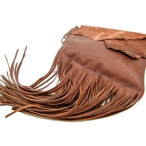 May include: A brown leather handbag with fringe detailing. The bag has a flap closure and a distressed leather look.
