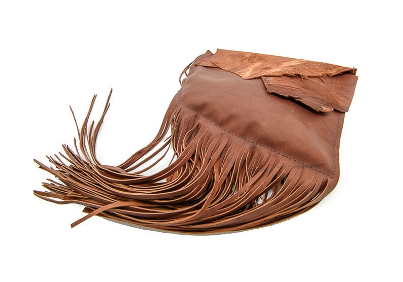 May include: A brown leather handbag with fringe detailing. The bag has a flap closure and a distressed leather look.