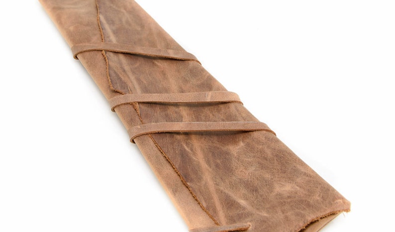 May include: A brown leather roll-up case with three straps to secure the contents. The case is made of distressed leather and has a rustic look.
