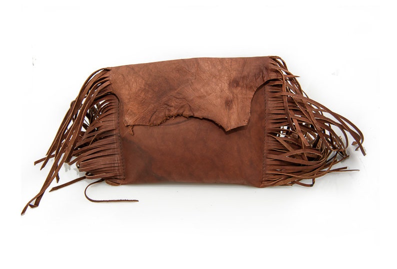 May include: A brown leather clutch bag with fringe detailing. The bag has a flap closure and a distressed look.