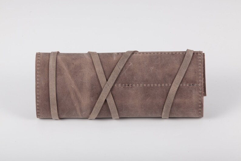May include: A gray leather clutch with a braided strap closure.