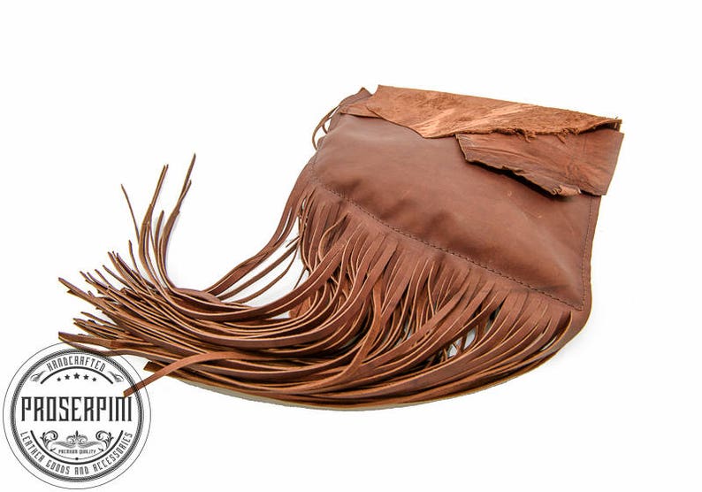 May include: A brown leather handbag with fringe detailing. The bag has a flap closure and a brown leather strap.