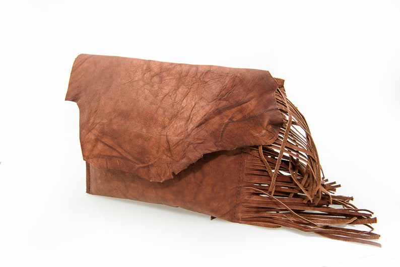 May include: A brown leather clutch with a fringe detail. The clutch has a textured surface and a flap closure.