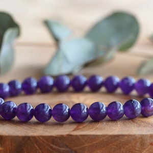 May include: A purple amethyst gemstone bracelet with round beads.