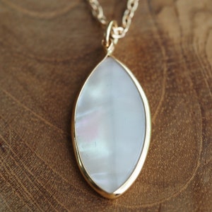 May include: A gold chain necklace with a white iridescent oval pendant.
