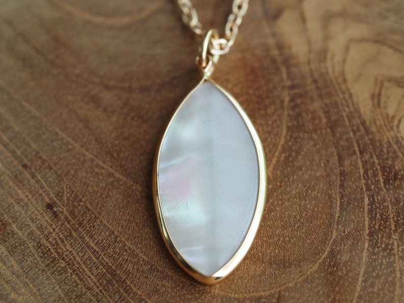 May include: A gold chain necklace with a white iridescent oval pendant.