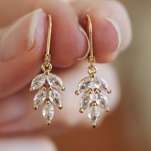 Puede incluir: Un par de pendientes colgantes de oro con cristales transparentes en forma de marquesa dispuestos en forma de hoja.