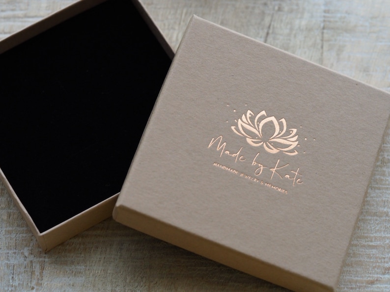 May include: A light brown square box with a black velvet interior. The box has a gold foil logo that says "Made by Kate" and "Handmade Jewelry & Memoires".