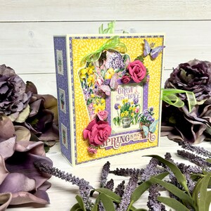 May include: A yellow and purple scrapbook with a floral design and the text "Grow with Love, Spring is in the Air". The scrapbook has a 3D butterfly and flowers.