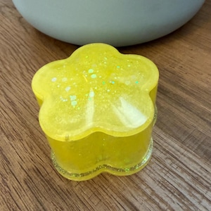 May include: A white ceramic mug with a black handle and the text "But First, Coffee" in a black, bold font. The mug is on a white surface. The mug is approximately 4 inches tall.