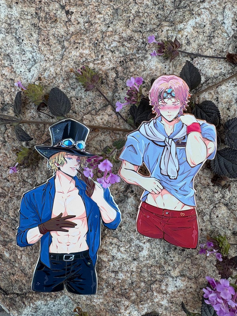 K&ouml;nnte beinhalten: Zwei Aufkleber mit Anime-Charakteren. Ein Aufkleber zeigt einen blonden Charakter in einer blauen Jacke, einer schwarzen Hose und einem Zylinder mit Brille. Der andere Aufkleber zeigt einen pinkhaarigen Charakter in einem blauen Hemd und roten Shorts.