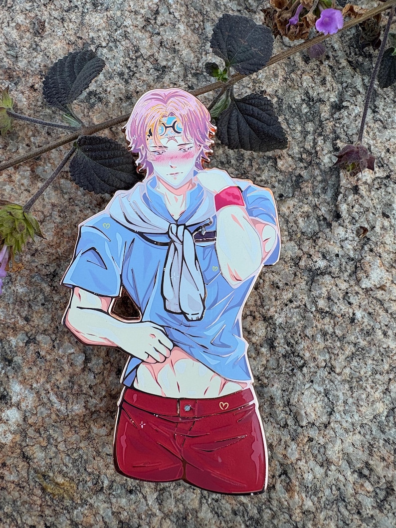 K&ouml;nnte beinhalten: Ein farbenfroher Anime-Pin mit einem m&auml;nnlichen Charakter in einem blauen Hemd und roten Shorts. Der Pin hat ein himmlisches Design auf der Stirn und ein Herzdetail auf den Shorts. Der Charakter hat rosa Haare und posiert auf suggestive Weise.