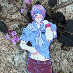 K&ouml;nnte beinhalten: Ein farbenfroher Emaille-Pin mit einem Anime-Charakter mit lila Haaren, einem blauen Stirnband und einem blauen Hemd. Die Figur tr&auml;gt weinrote Shorts mit einem Herzdetail. Der Pin ist vor einem Naturstein-Hintergrund mit lila Blumen platziert.