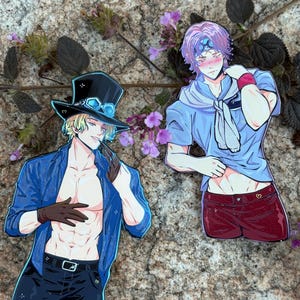 K&ouml;nnte beinhalten: Zwei Aufkleber mit Anime-Charakteren. Einer zeigt einen blonden Charakter in einer blauen Jacke, schwarzen Shorts und einem Zylinder. Der andere ist ein Charakter mit lila Haaren, einem blauen Hemd und roten Shorts. Beide sind auf einer Steinoberfl&auml;che abgebildet.