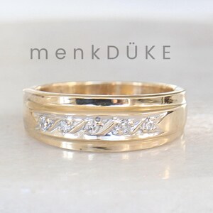 Könnte beinhalten: Ein Goldband mit einer Reihe kleiner Diamanten, die in einem wellenförmigen Muster gesetzt sind. Das Band hat eine polierte Oberfläche.