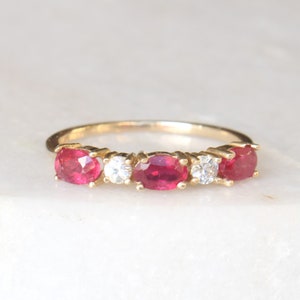Peut inclure: Une bague en or avec cinq pierres précieuses de forme ovale. Les trois pierres centrales sont rouges et les deux pierres extérieures sont claires.