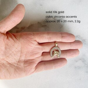 May include: Gold horseshoe pendant with cubic zirconia accents. The pendant is approximately 20 x 20 mm and weighs 2.2 grams.