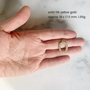 May include: A gold horseshoe charm made of solid 10k yellow gold. The charm is approximately 1.9 cm by 1.75 cm and weighs 1.65 grams.