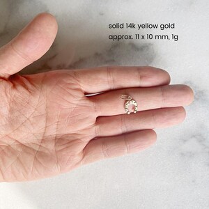 May include: A solid 14k yellow gold horseshoe charm, approximately 11 x 10 mm, weighing 1 gram. The charm is shown in a hand, with the horseshoe facing the viewer.