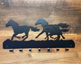 May include: Black metal key rack with a silhouette of three horses running. The rack has six hooks.