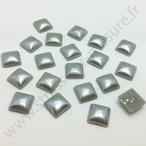 May include: A collection of 20 silver square-shaped rhinestones. The rhinestones have a slightly domed shape and a shiny, reflective surface.