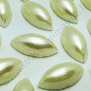 May include: A group of off-white pearlescent oval-shaped beads with a hole at the top. The beads are arranged in a random pattern on a white surface.