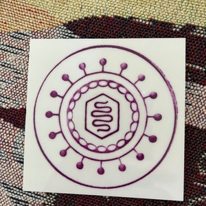 May include: A purple and white sticker with a stylized image of a virus. The virus has a hexagonal shape in the center with a squiggly line inside. The virus is surrounded by a circle of dots.