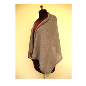 May include: A gray knitted shawl with a crocheted trim. The shawl is draped over a mannequin.