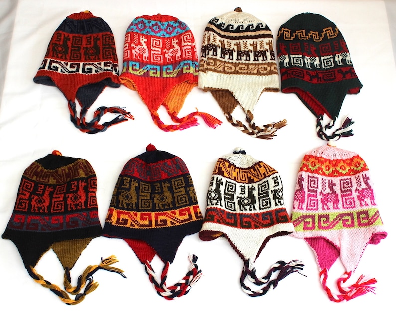 May include: Eight colorful knit hats with ear flaps and braided ties. The hats feature geometric patterns and llama designs in various colors, including red, blue, green, and pink. The hats are displayed on a white surface.