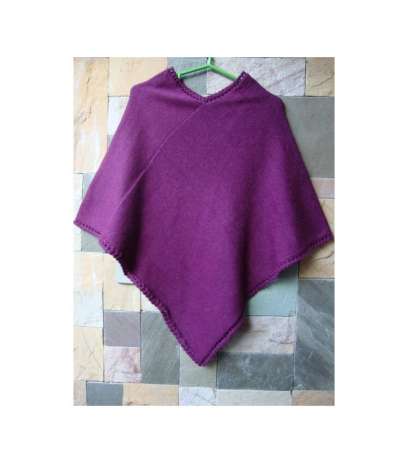 Pode incluir: Um poncho de malha roxa com uma borda de croch&ecirc;.