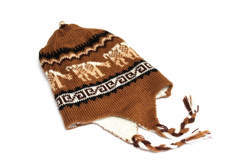 May include: A brown knit hat with ear flaps and a braided tassel. The hat features a repeating pattern of white and tan llamas and geometric designs. The hat is made of a soft, warm material.