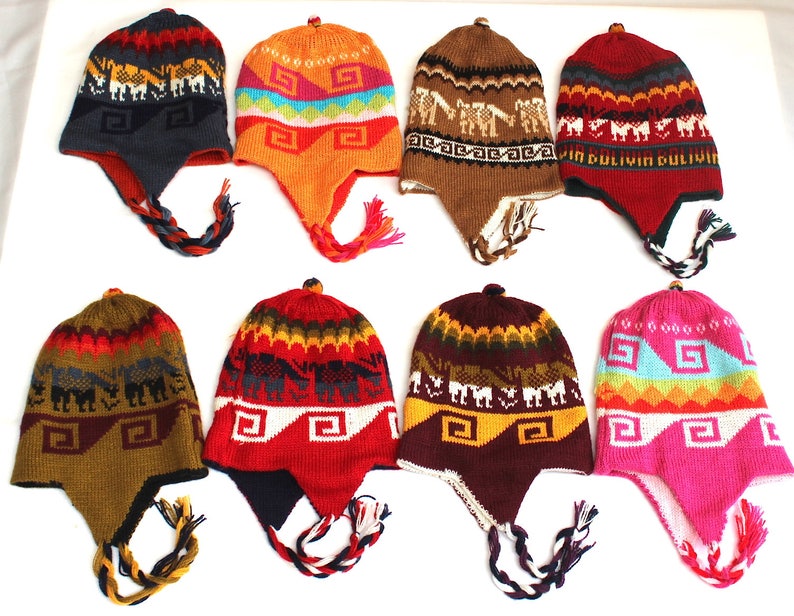 May include: A collection of eight colorful knit hats with ear flaps and braided tassels. The hats feature geometric and animal patterns in various colors, including red, orange, blue, and brown. Each hat has a small pom-pom on top.