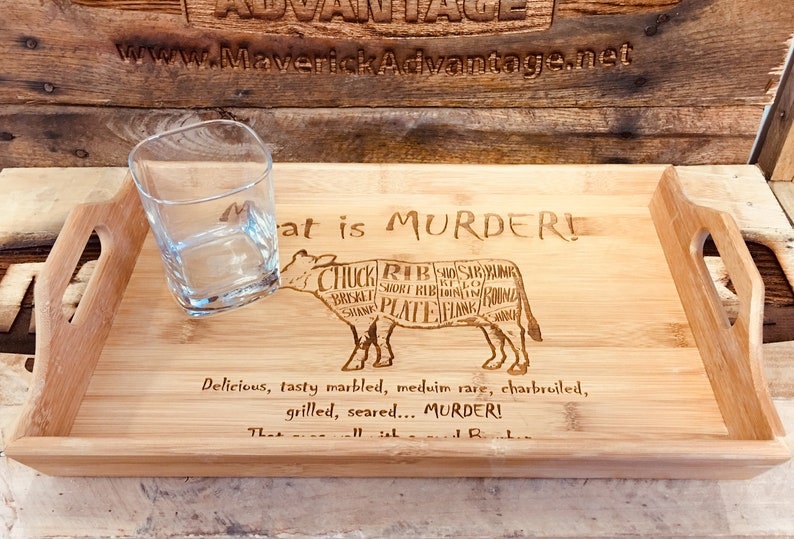 May include: A wooden serving tray with a cow cut-out design and the text "Meat is Murder!"  The cow is labeled with different cuts of meat. The tray has two handles on the sides.