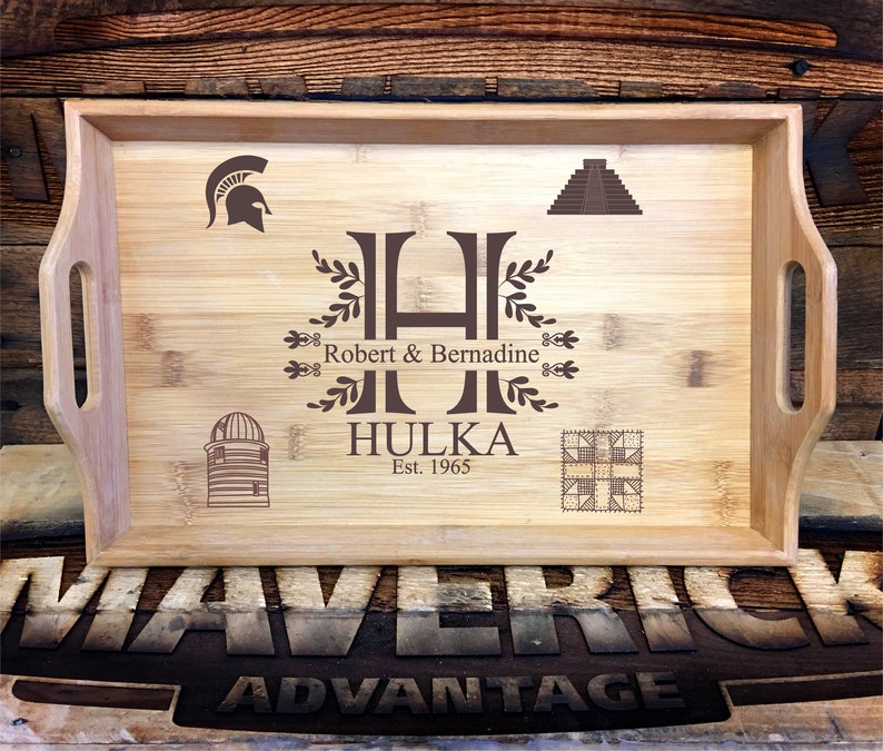 May include: A personalized wooden serving tray with a brown engraved design. The tray features a large letter "H" with a leafy design, the names "Robert & Bernadine", the last name "Hulka", and the year "Est. 1965". The tray also features a Spartan helmet, a pyramid, a silo, and a quilt block.