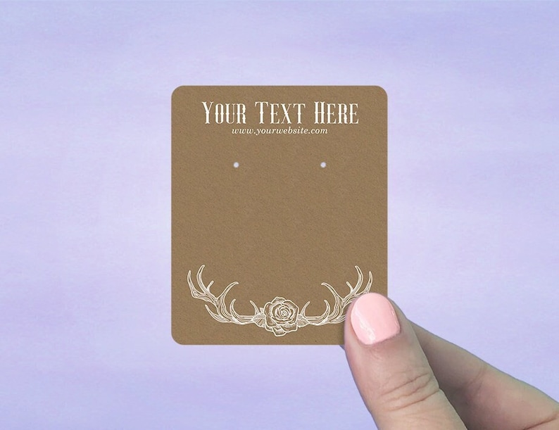 May include: Brown card stock earring display card with two holes for earrings. The card has a white design of antlers and a rose. The text "YOUR TEXT HERE" and "www.yourwebsite.com" is printed on the card.