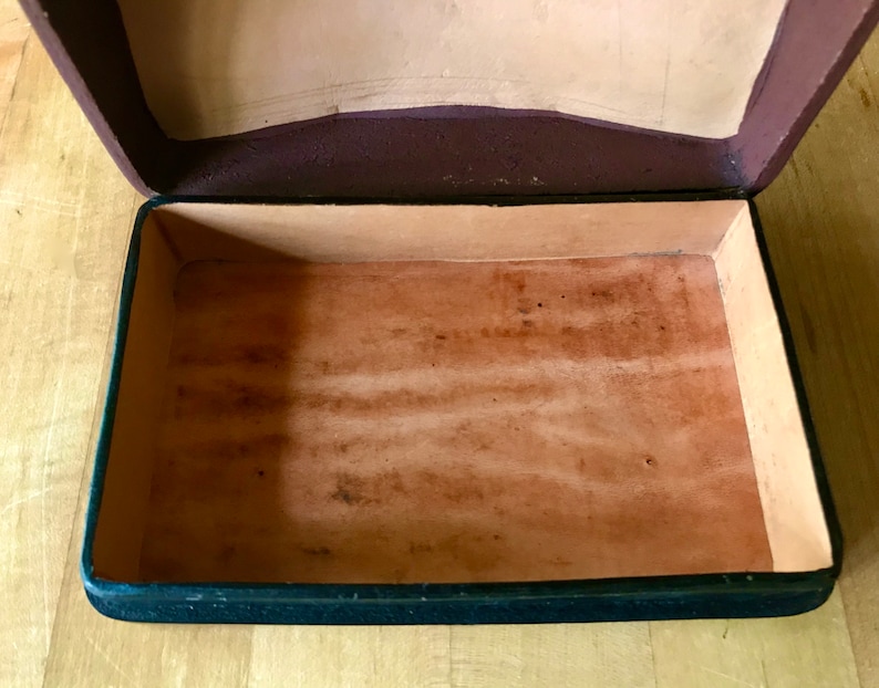 May include: An empty, black leather box with a brown leather interior. The box is open and the interior is visible.
