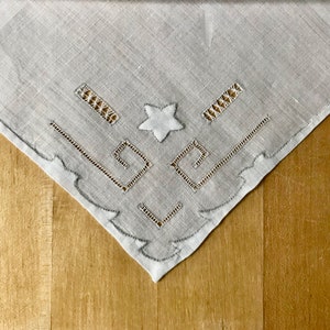 May include: A white linen tablecloth with a delicate embroidered design featuring a star and geometric patterns.