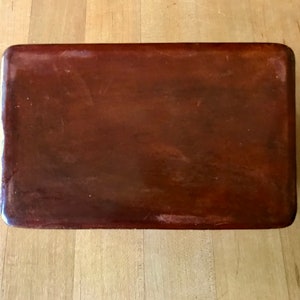 May include: A rectangular wooden box with a dark brown finish. The box has a smooth, polished surface.