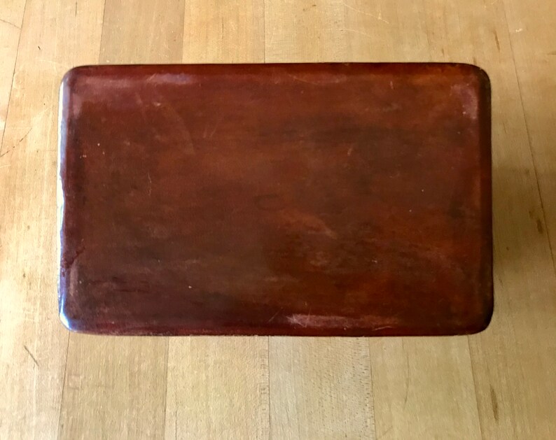 May include: A rectangular wooden box with a dark brown finish. The box has a smooth, polished surface.