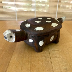 May include: A small wooden turtle box with white polka dots. The box is closed and has a hinged lid.