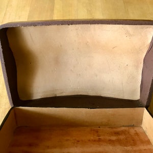 May include: An empty brown box with a light brown interior. The box is open and the lid is propped up.