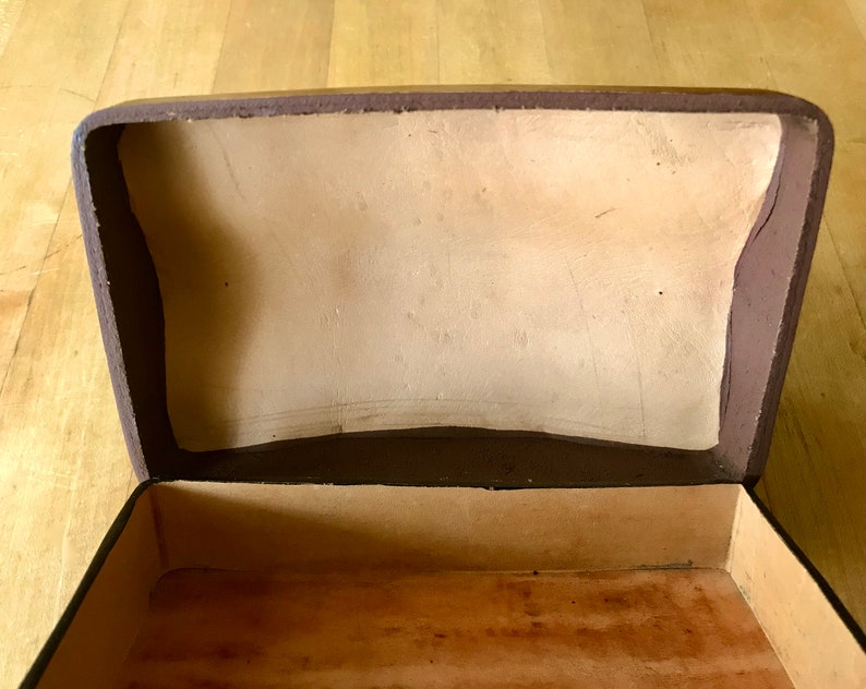 May include: An empty brown box with a light brown interior. The box is open and the lid is propped up.