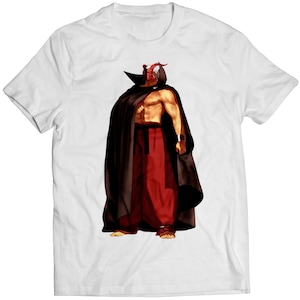 May include: A white t-shirt with a graphic print of a masked figure wearing a red and white mask, a black cape, and red pants.