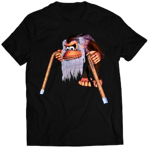 Puede incluir: Camiseta negra con una imagen de dibujos animados de Donkey Kong en su vejez, sosteniendo dos bastones.