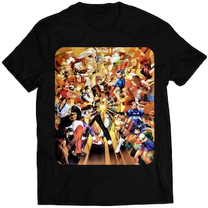 May include: Black t-shirt with a colorful graphic print of characters from the Street Fighter video game series. The characters are arranged in a dynamic pose, with a bright yellow glow emanating from the center of the image.