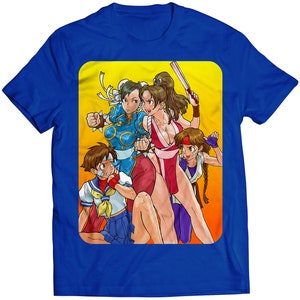 May include: A blue t-shirt with a graphic of four female characters from a video game. The characters are in a fighting pose and are surrounded by a yellow background.
